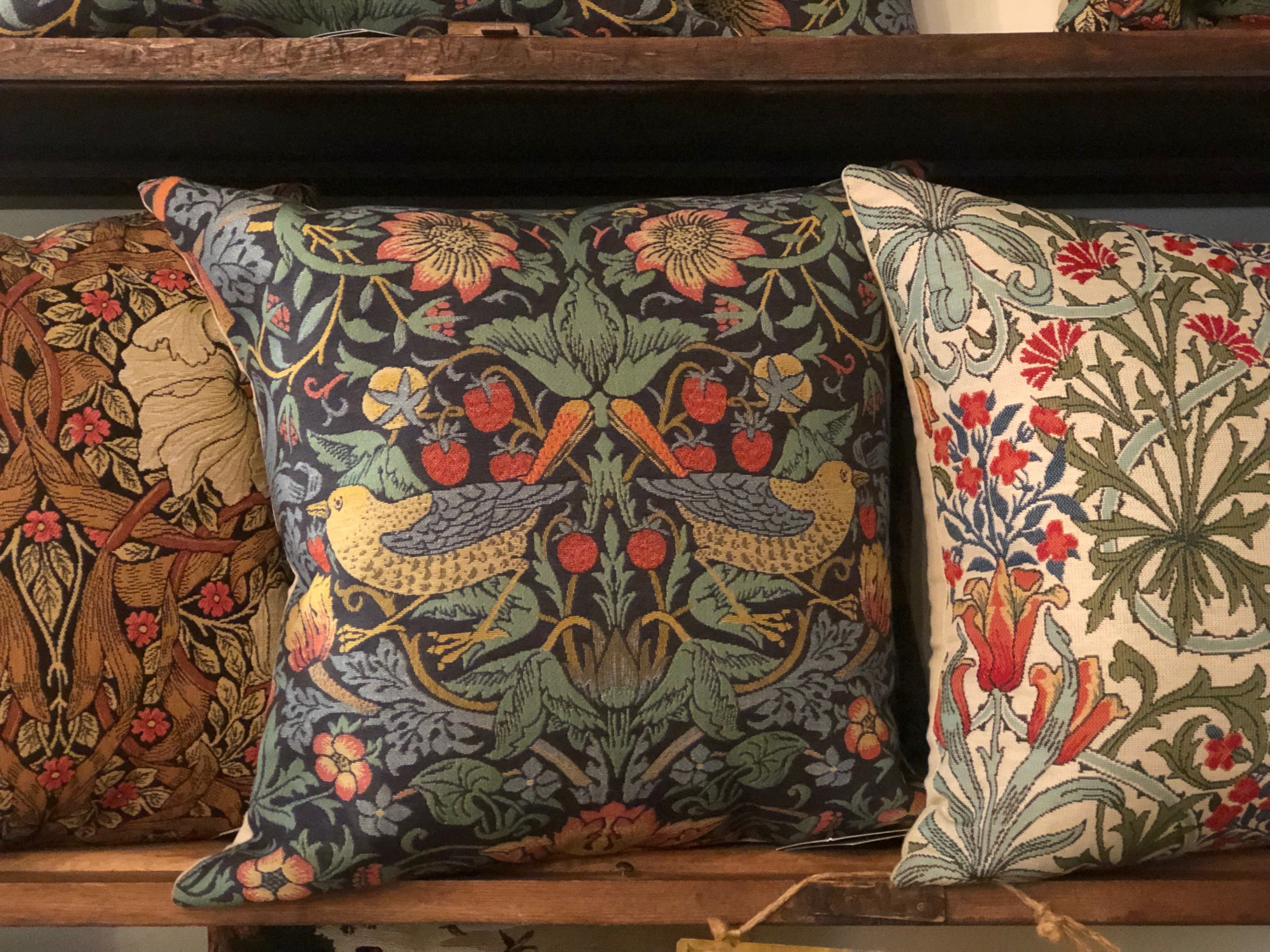 3 William Morris pillows on a shelf. 